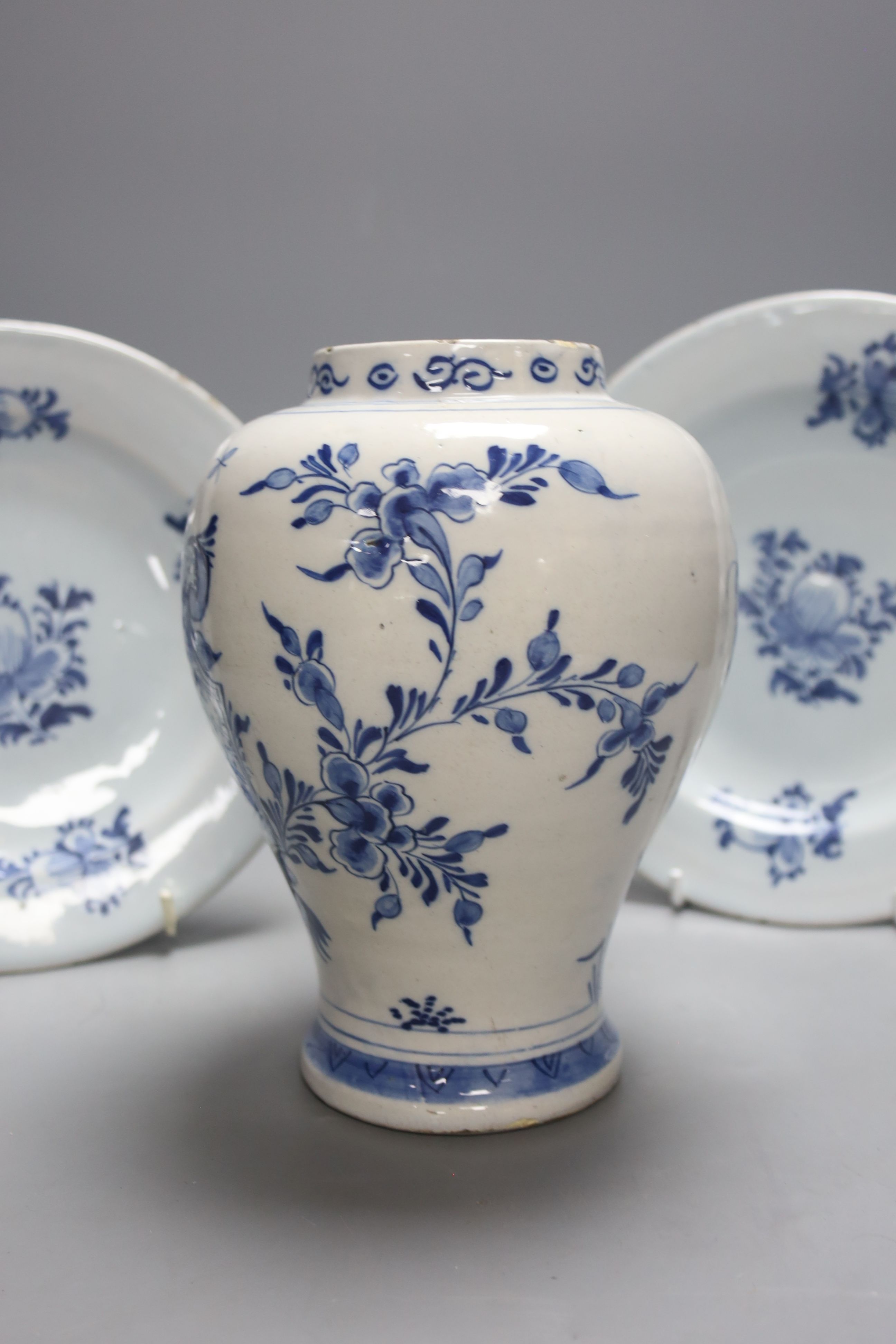 A mid-18th century Dutch Delft flower and fence-decorated blue and white baluster vase, a similar plate and a pair of English delft plates, H 20cm (vase)